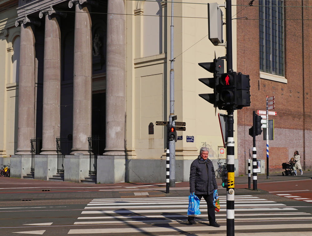 man in black jacket standing near traffic light during daytime