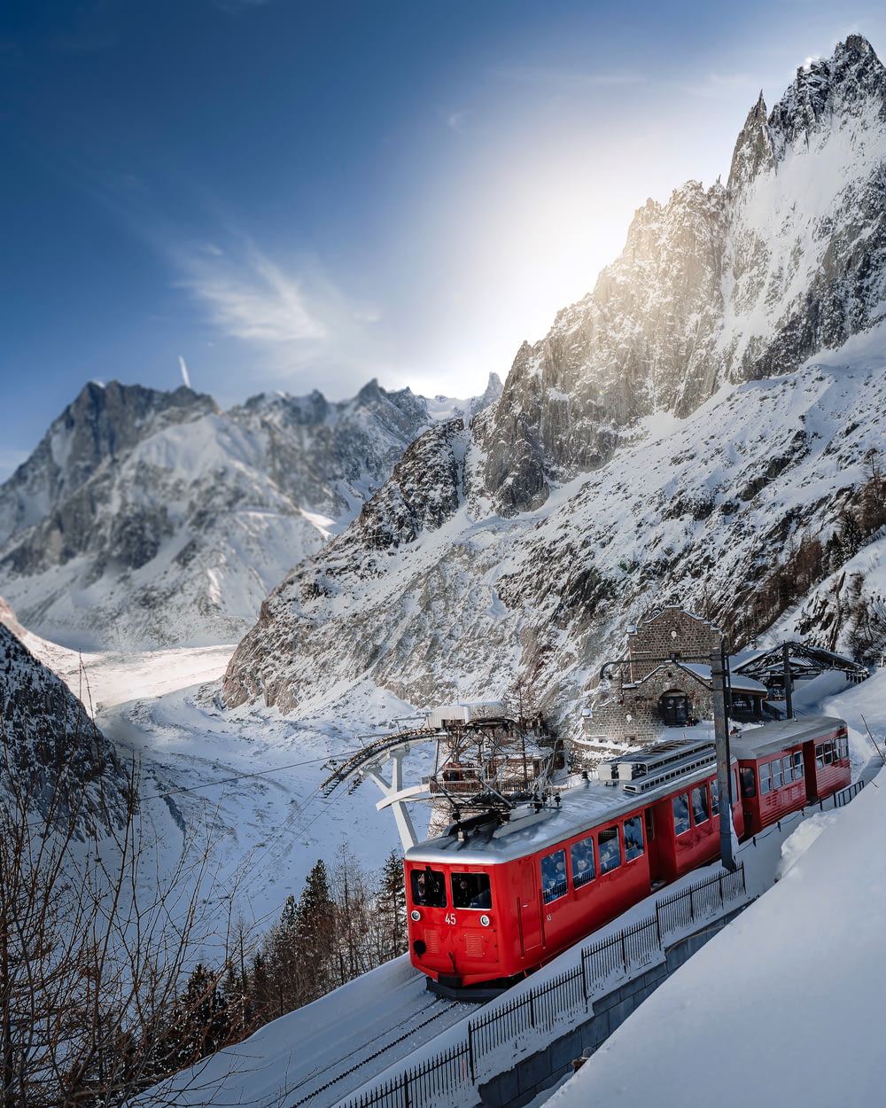 trem vermelho e branco na montanha coberta de neve durante o dia