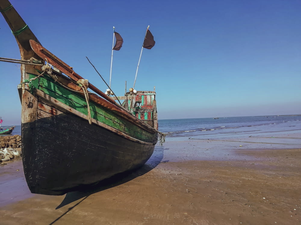 green and brown boat on beach during daytime