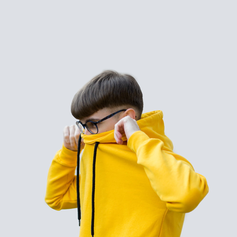boy in yellow hoodie covering his face