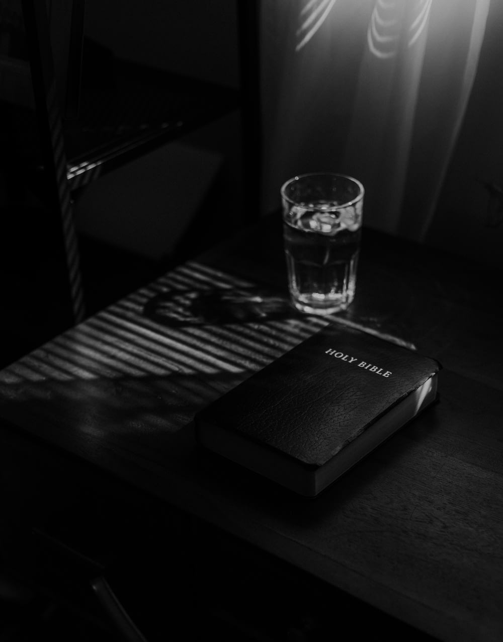 grayscale photo of clear drinking glass on table