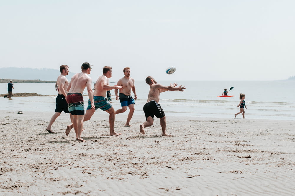group of people playing beach volleyball on beach during daytime