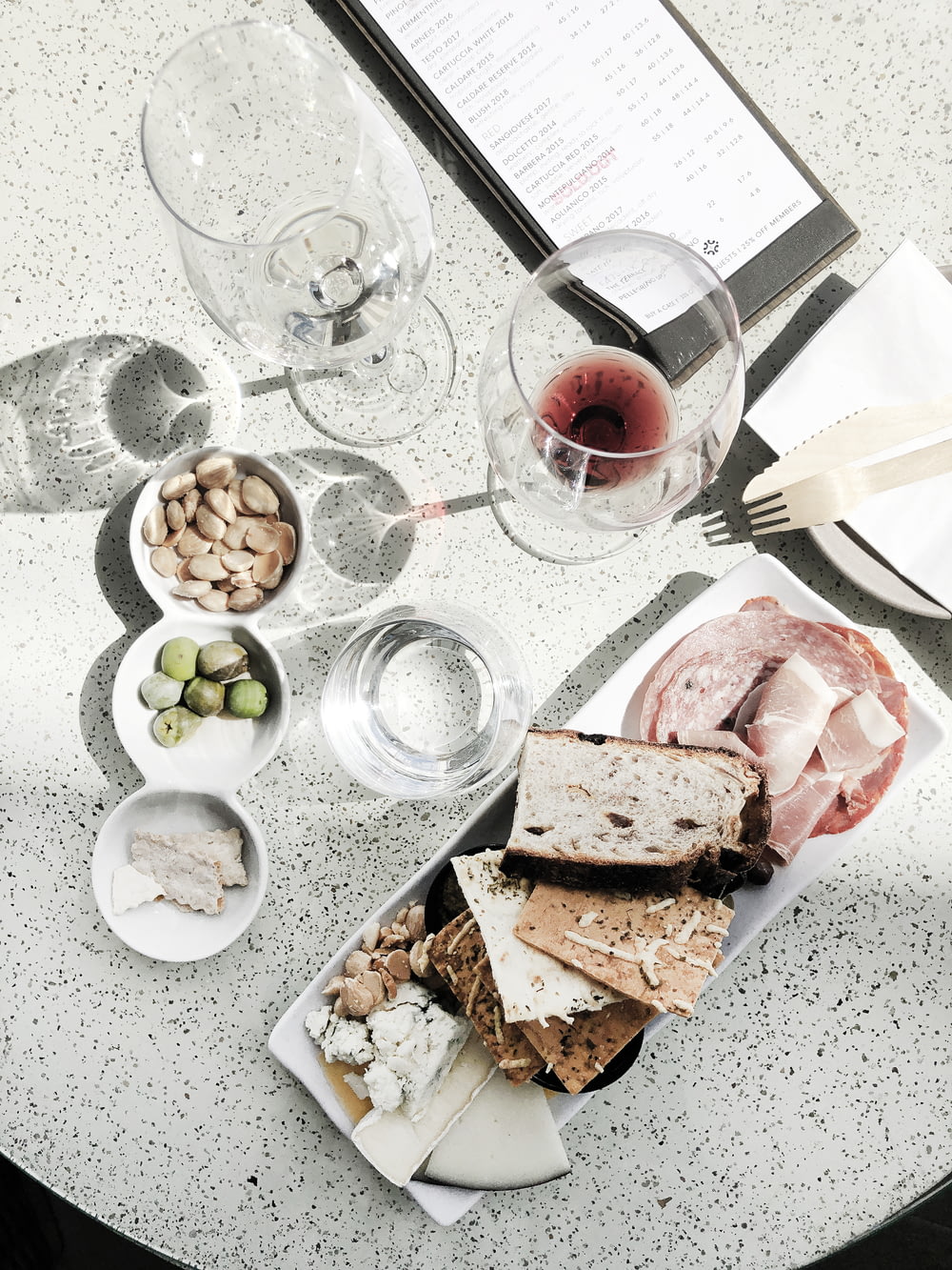pain tranché sur assiette en céramique blanche à côté d’un verre à vin transparent