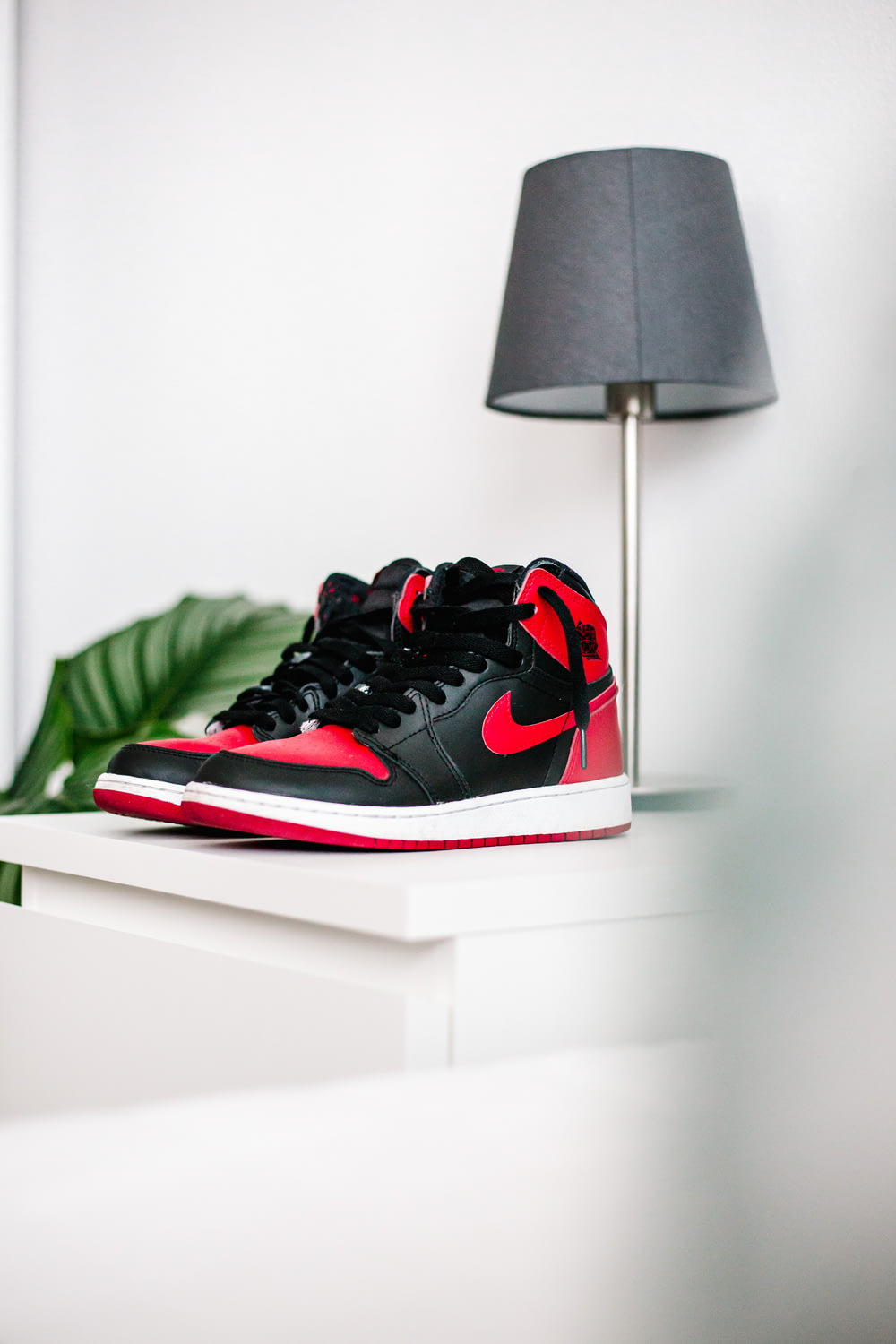 black and red nike sneakers on white table