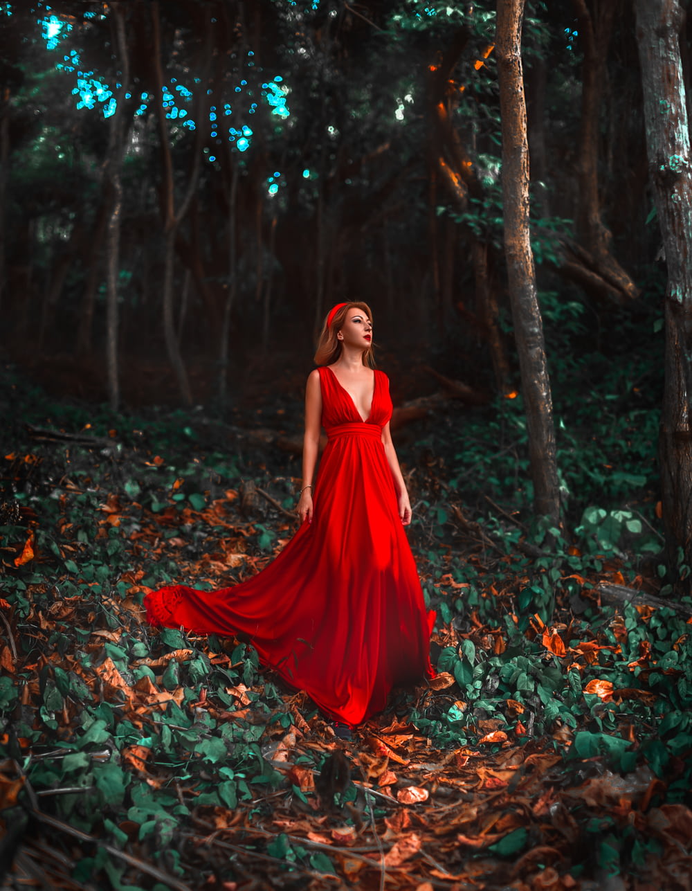 donna in vestito rosso in piedi su foglie secche