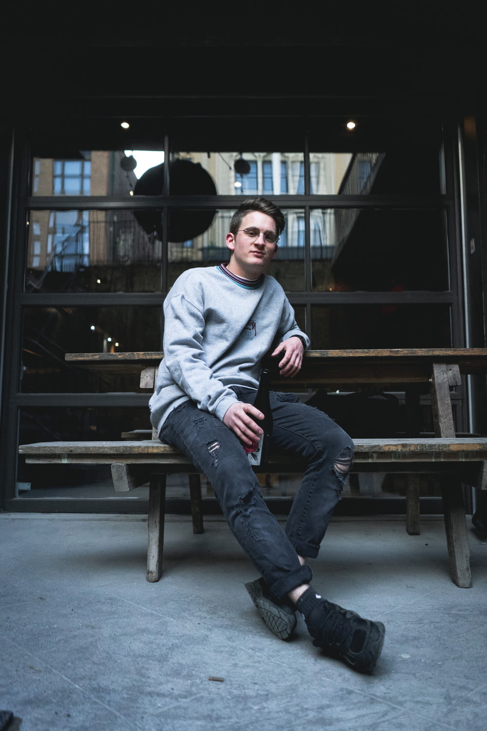 man in gray hoodie sitting on brown wooden bench