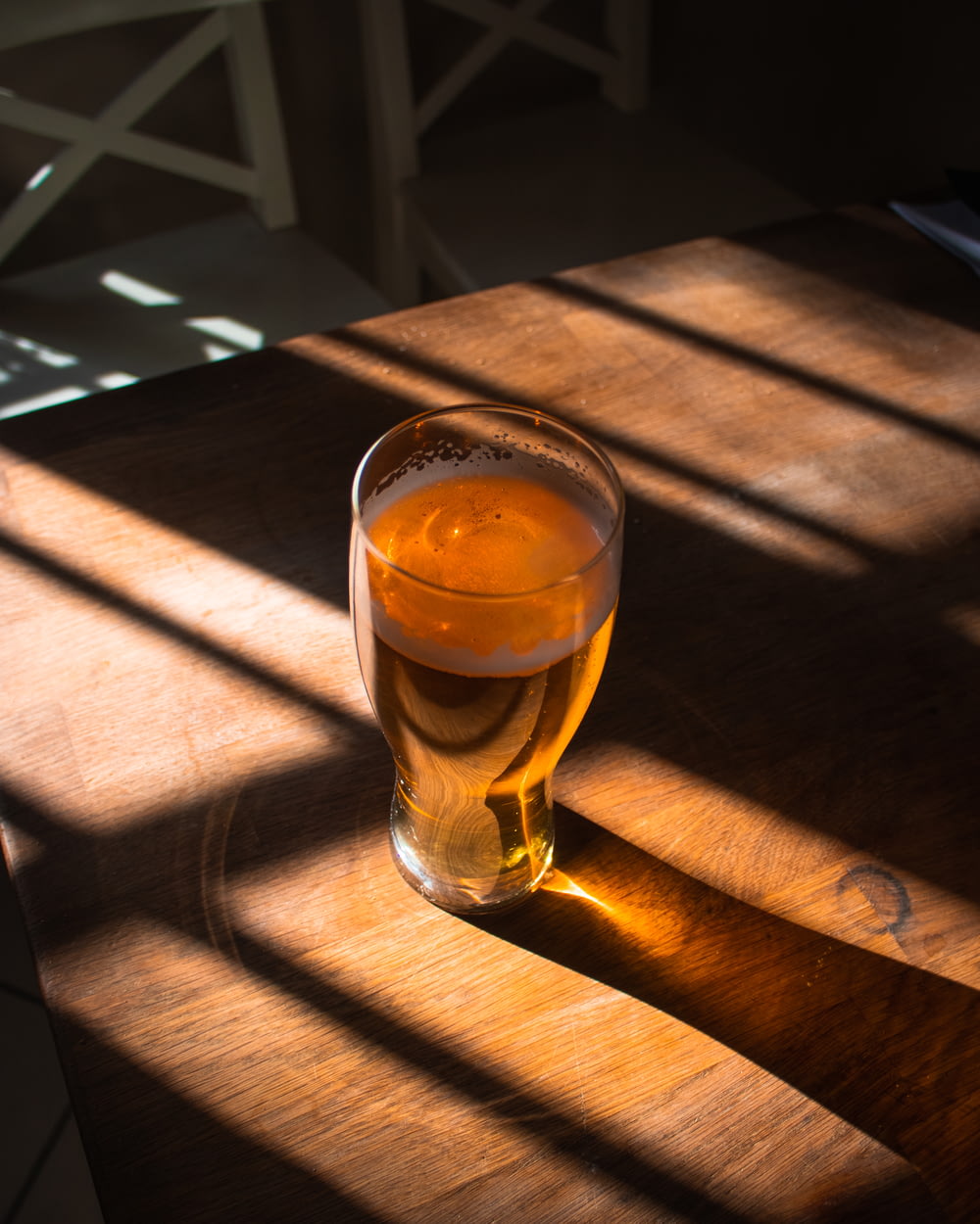 茶色の木製のテーブルの上に茶色の液体が入った透明なコップ