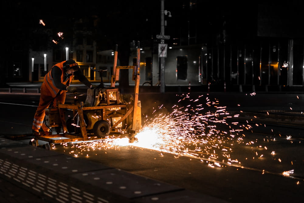 man in orange shirt riding on yellow heavy equipment during night time