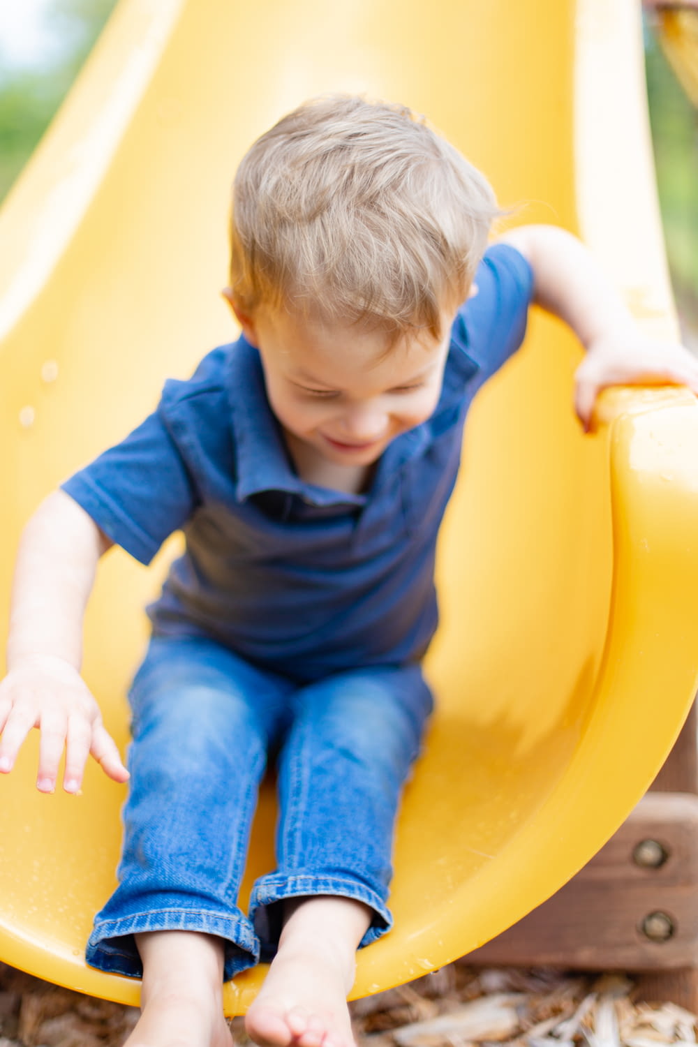 boy in blue t-shirt and blue denim jeans sitting on yellow plastic chair
