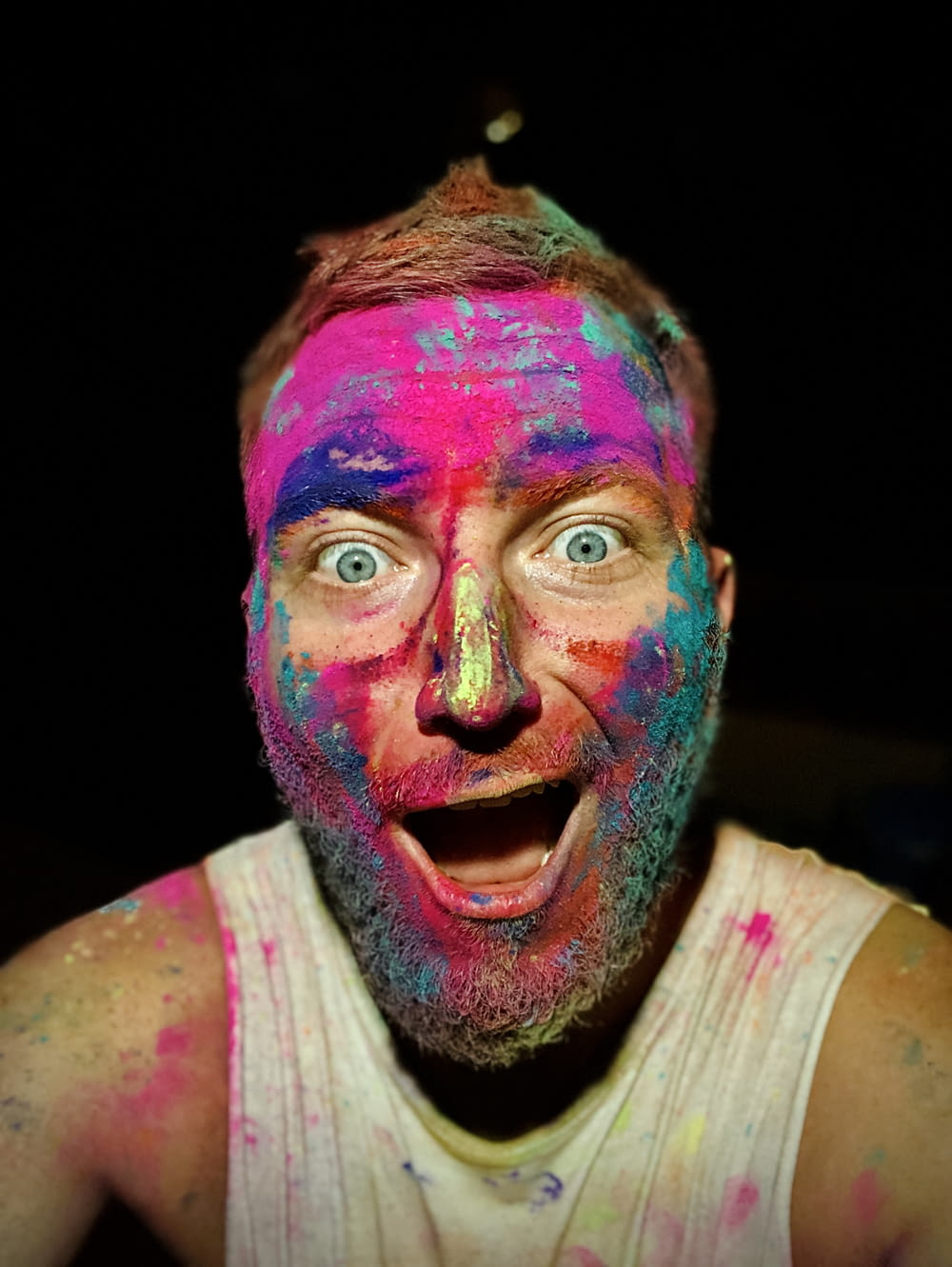 man in white tank top with pink and blue paint on face