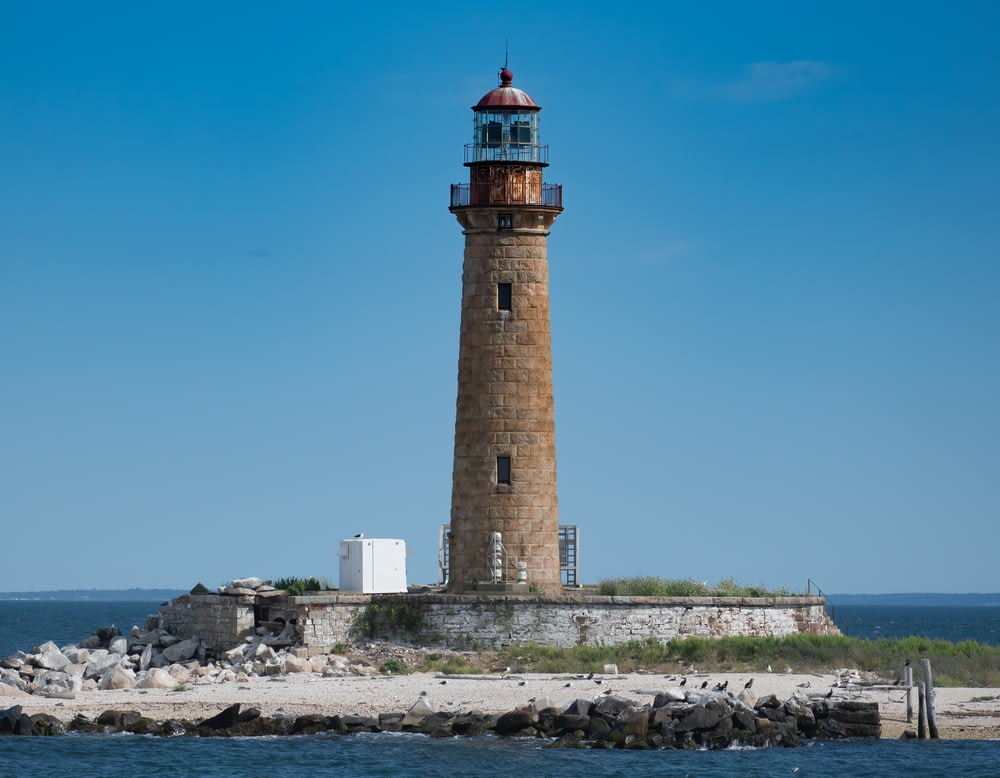 brown and white lighthouse near body of water during daytime