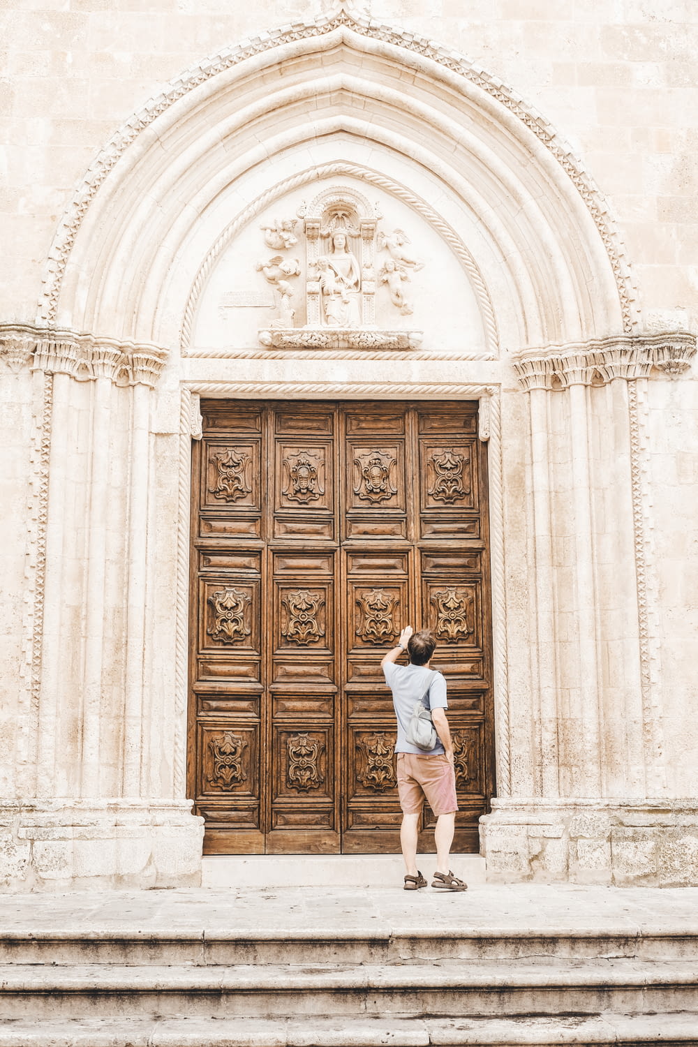 woman in white shirt standing in front of brown wooden door