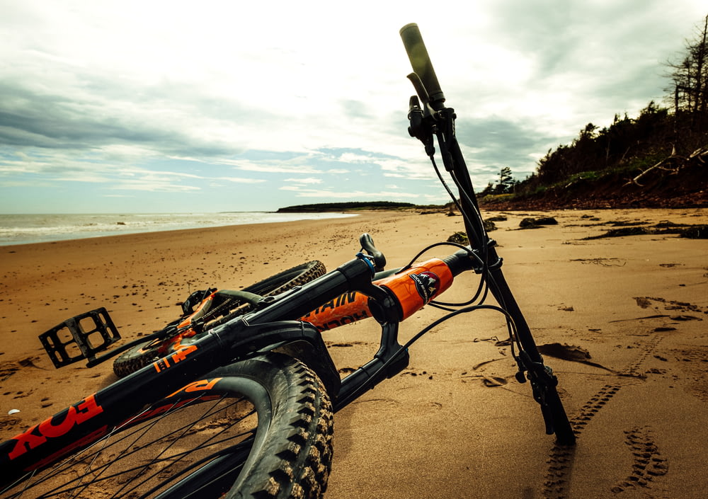 Bicicleta negra y naranja sobre arena marrón durante el día
