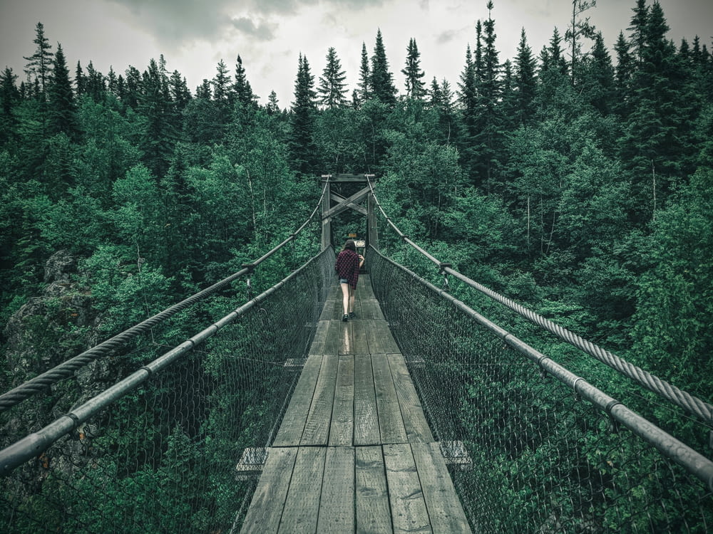 Persona in giacca nera che cammina sul ponte sospeso