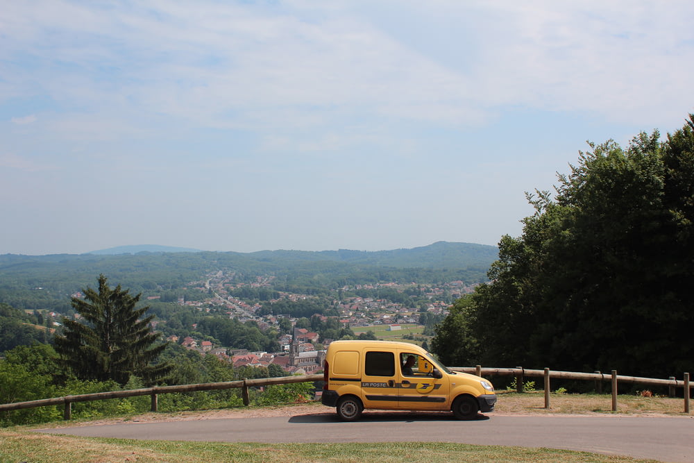 yellow van on road near green trees during daytime