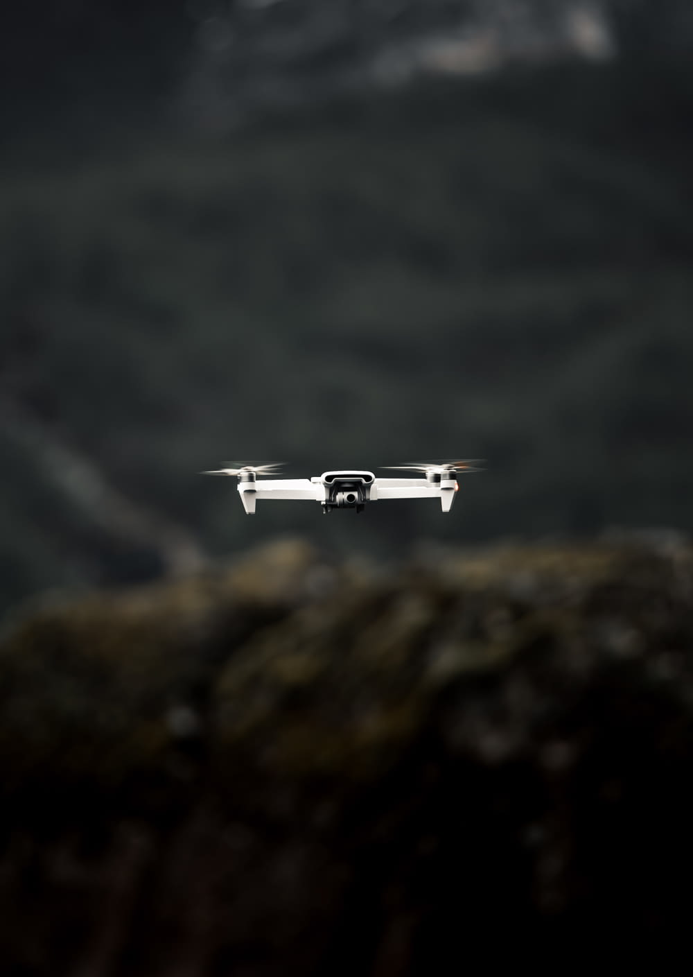 white drone flying over the mountain