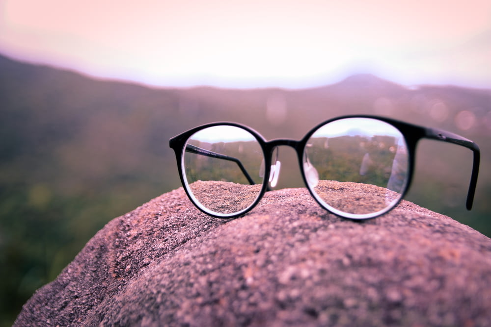 black framed eyeglasses on brown rock