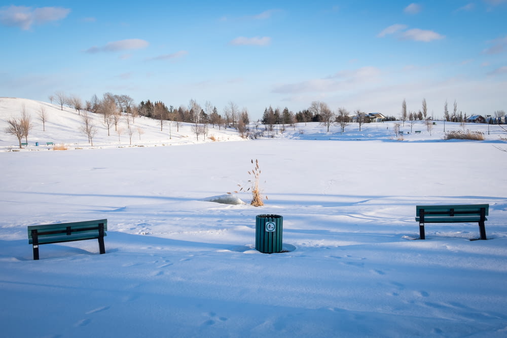 green trash bin on snow covered ground during daytime