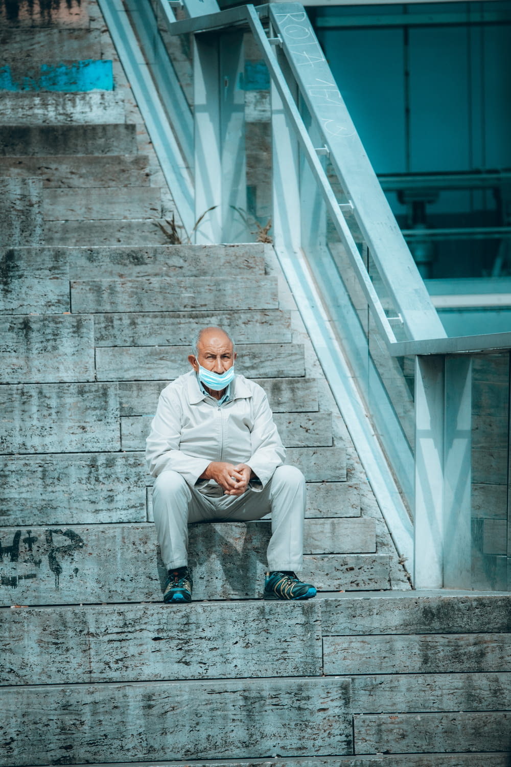 man in white dress shirt and gray pants sitting on gray concrete stairs