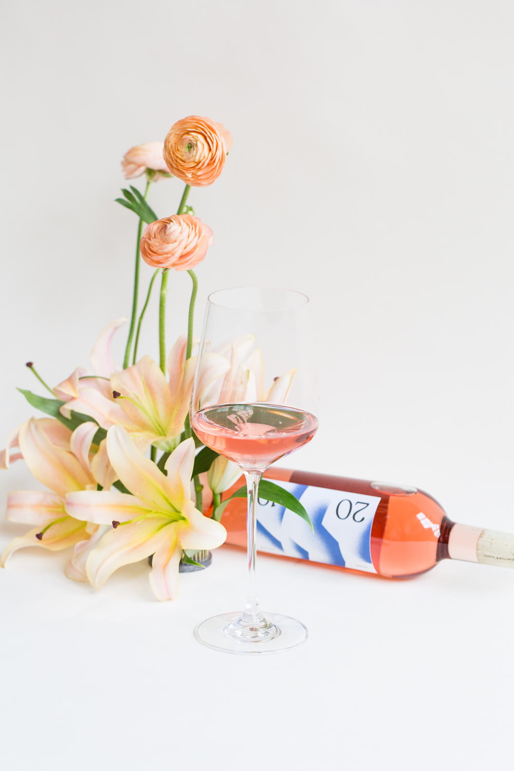 weiße Blumen neben Weinflasche und Weinglas
