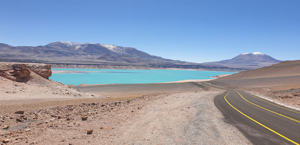blue body of water near mountain under blue sky during daytime