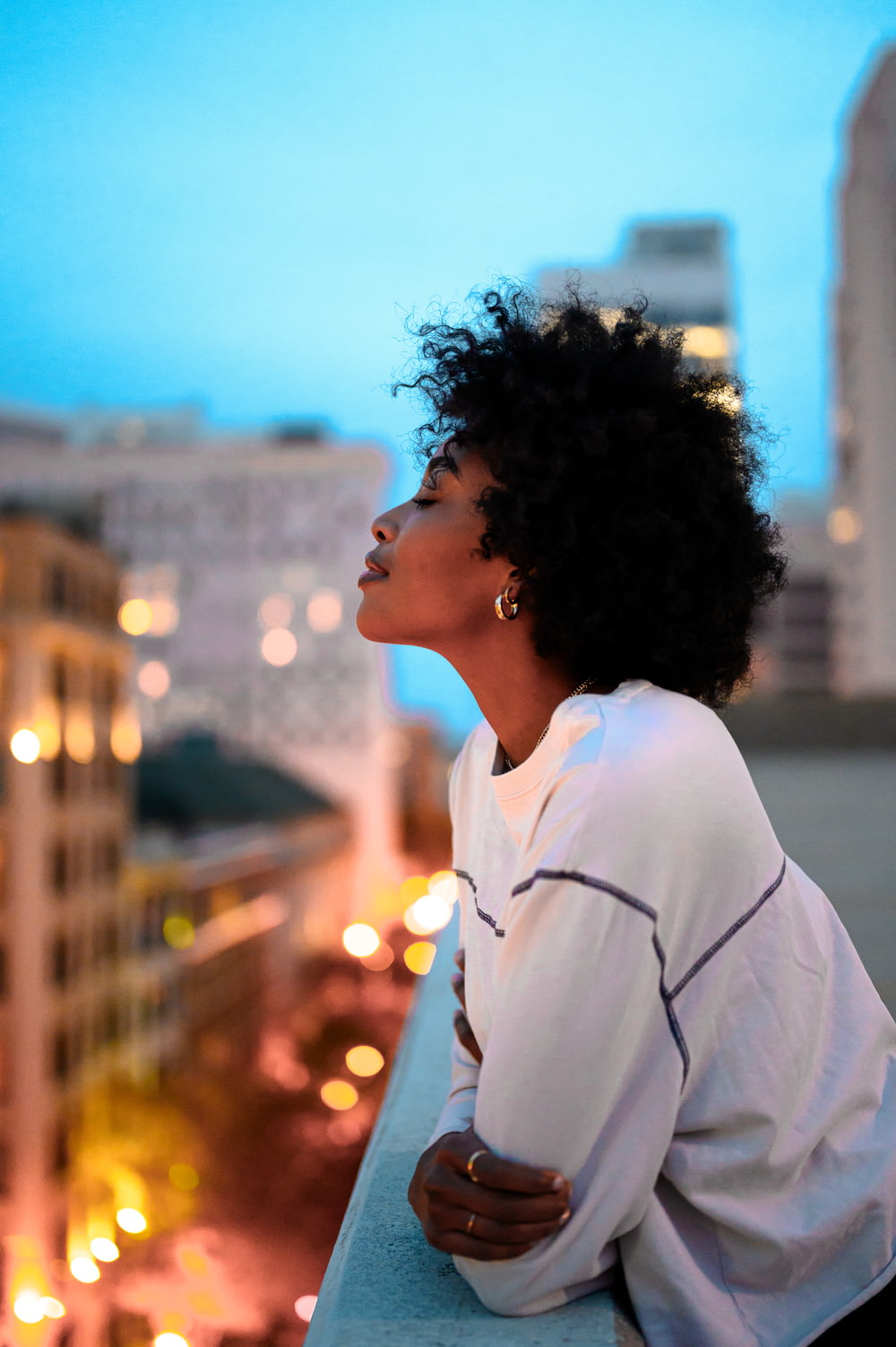 femme en chemise à col blanc regardant la ville pendant la nuit