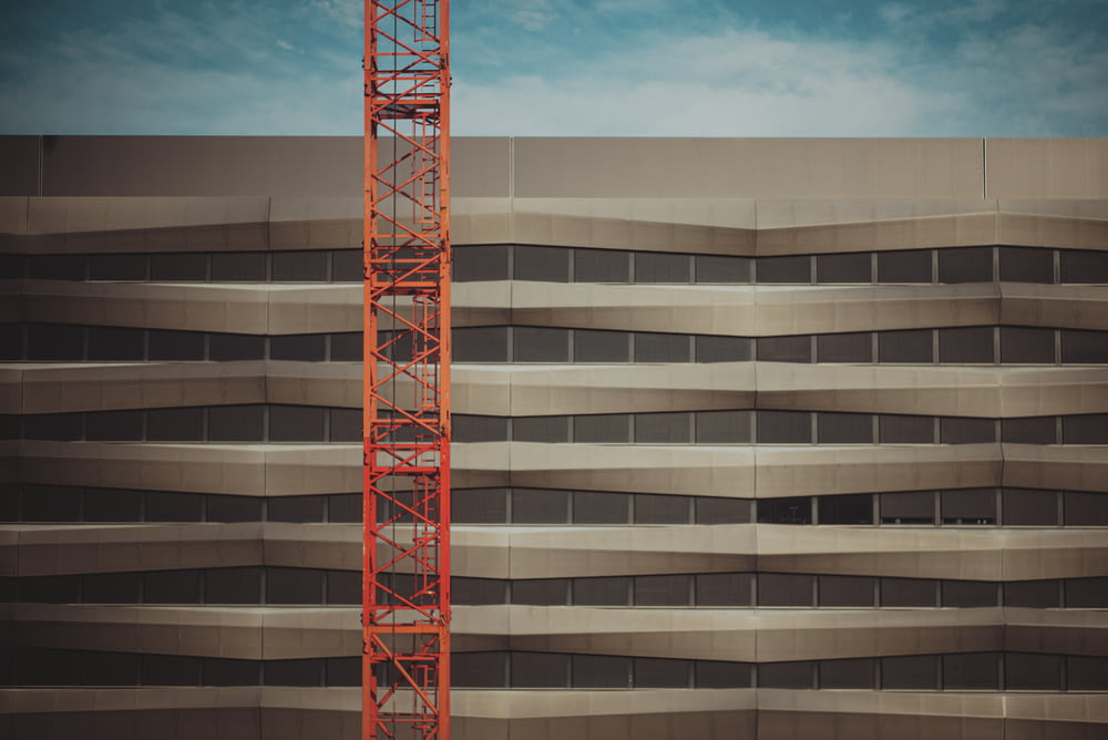 red metal crane near brown concrete building during daytime