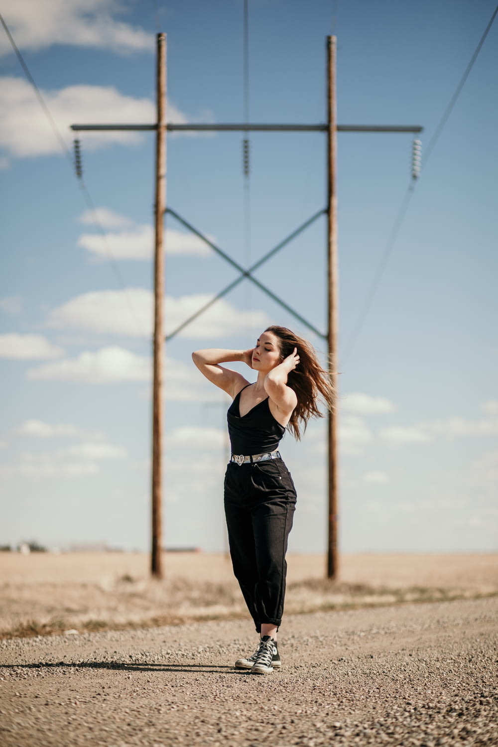 woman in black tank top and black pants standing on brown field during daytime