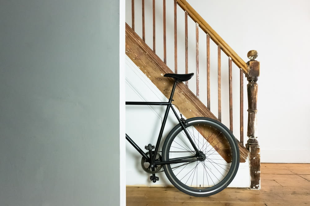 bicicletta nera e grigia appoggiata al muro bianco