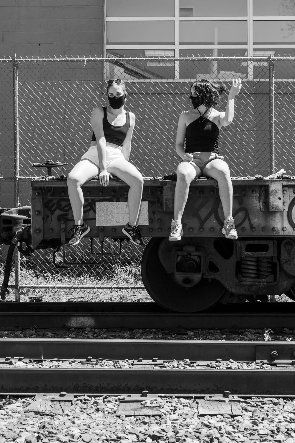 woman in black tank top and white panty sitting on train rail