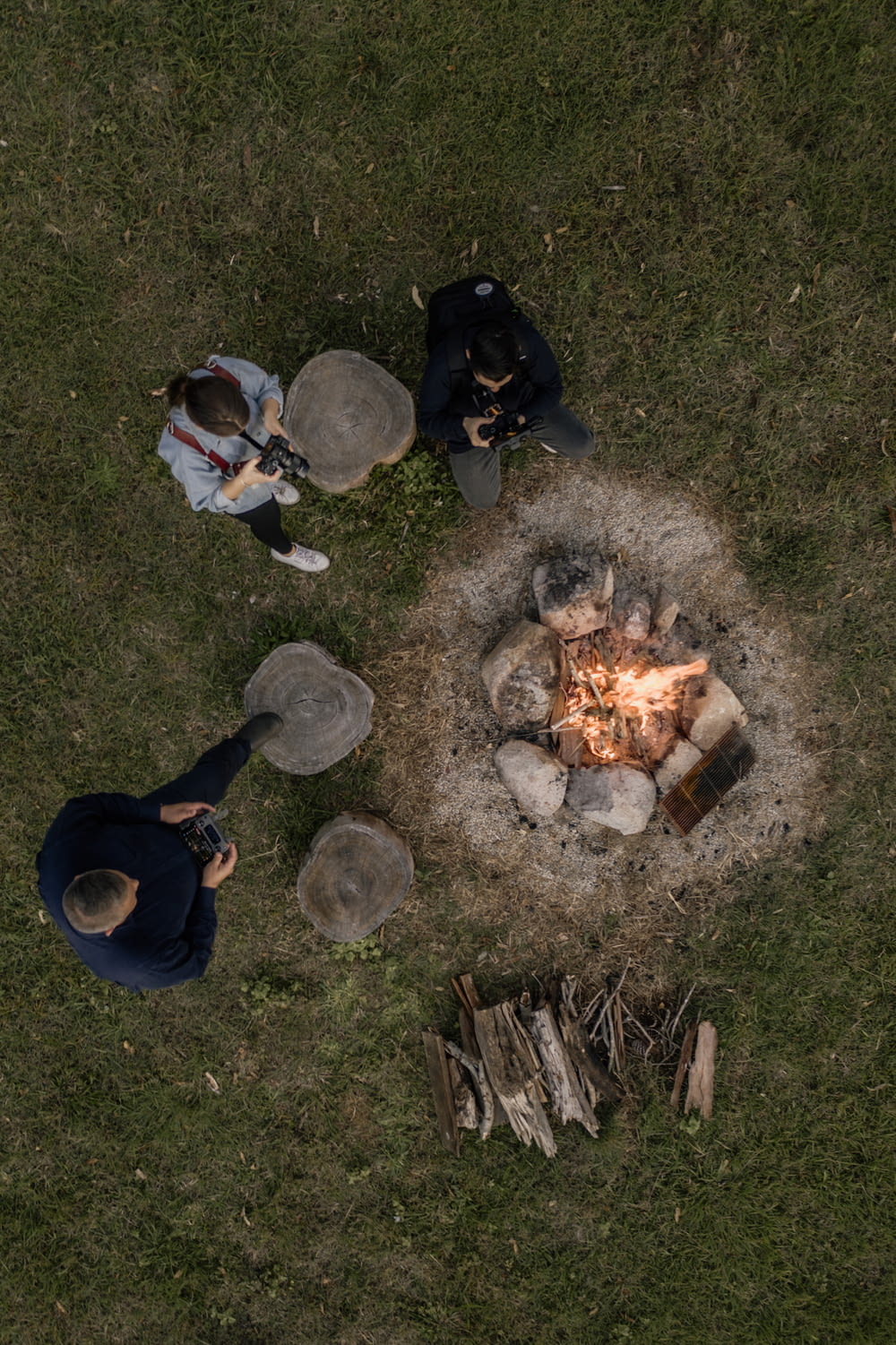 people sitting on grass field near bonfire during daytime