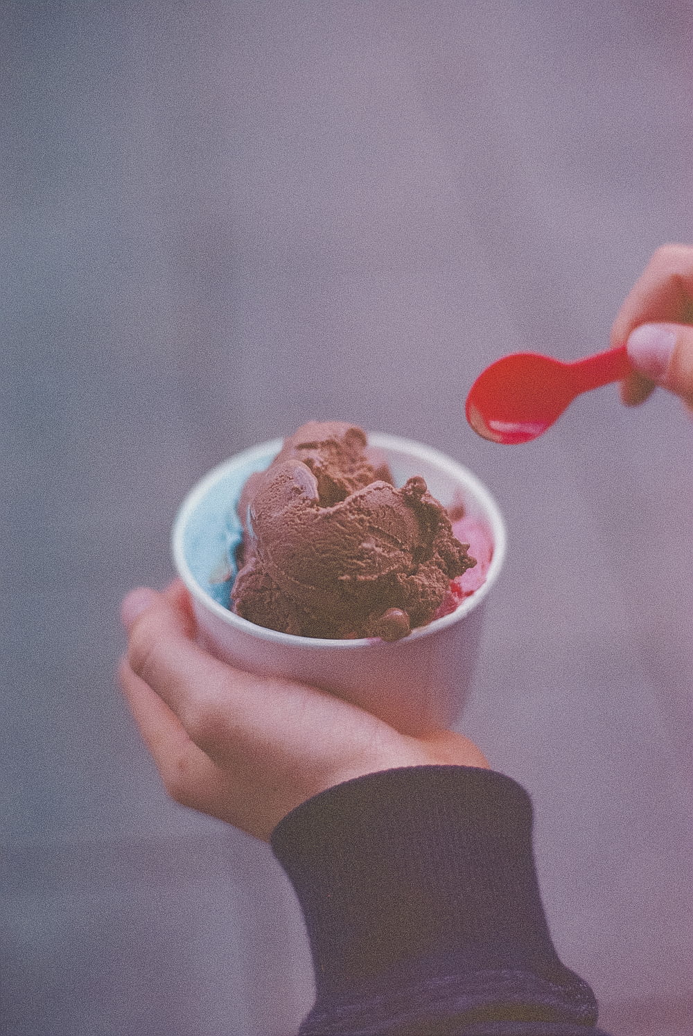 person holding ice cream with red spoon