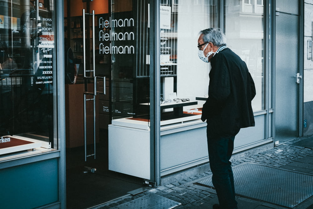 um homem em pé na frente de uma vitrine de loja