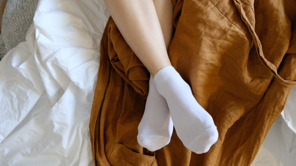 persona con calcetines blancos acostada en la cama