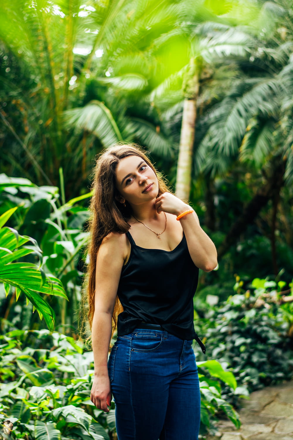 woman in black tank top and blue denim shorts standing near green plants during daytime