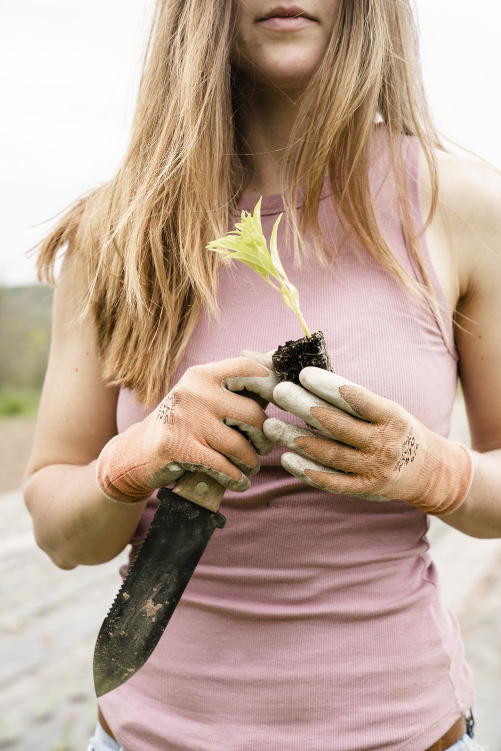 woman in pink tank top holding green plant