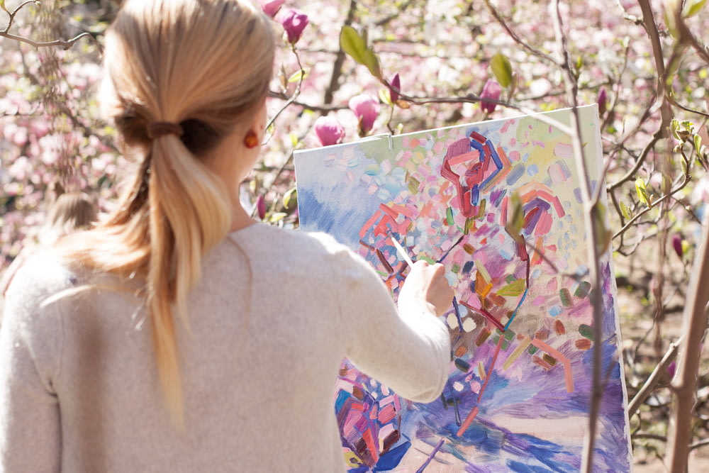 woman in white long sleeve shirt holding white and blue floral painting