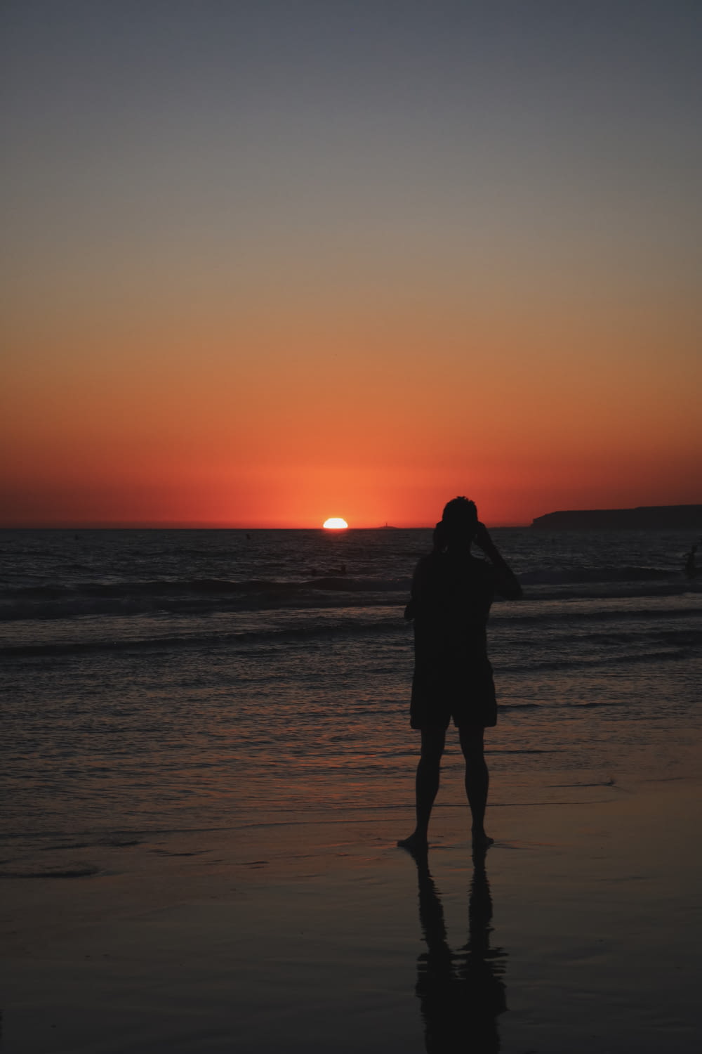silhouette di donna in piedi sulla spiaggia durante il tramonto