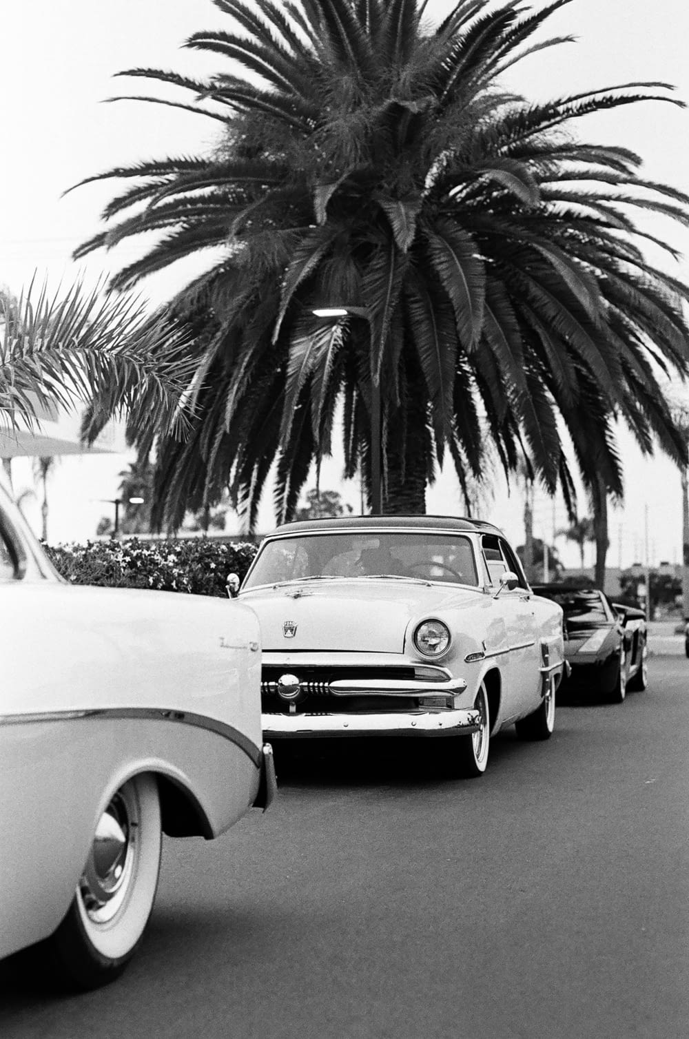 grayscale photo of classic car parked on the side of the road