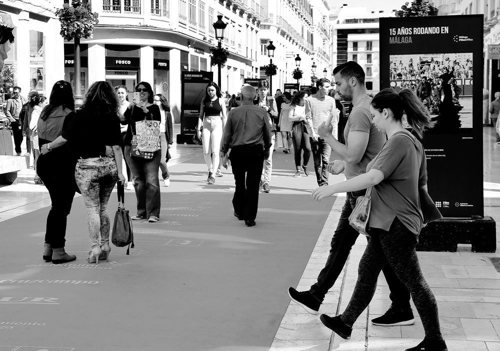 Photo en niveaux de gris d’une femme en débardeur et pantalon marchant dans la rue