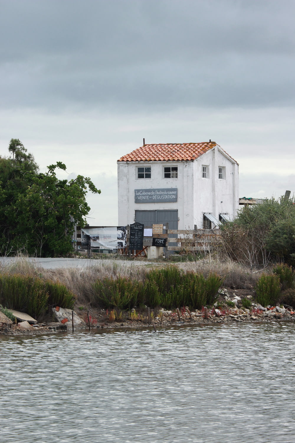 Casa de concreto branco ao lado do corpo de água durante o dia