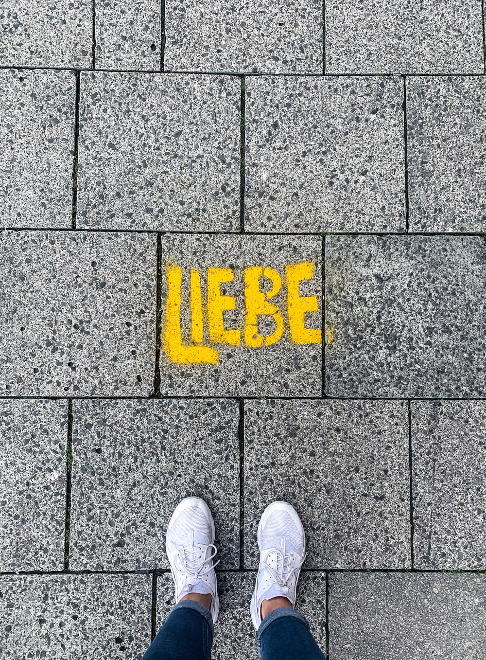 a person standing in front of a sidewalk with the word liebe painted on it