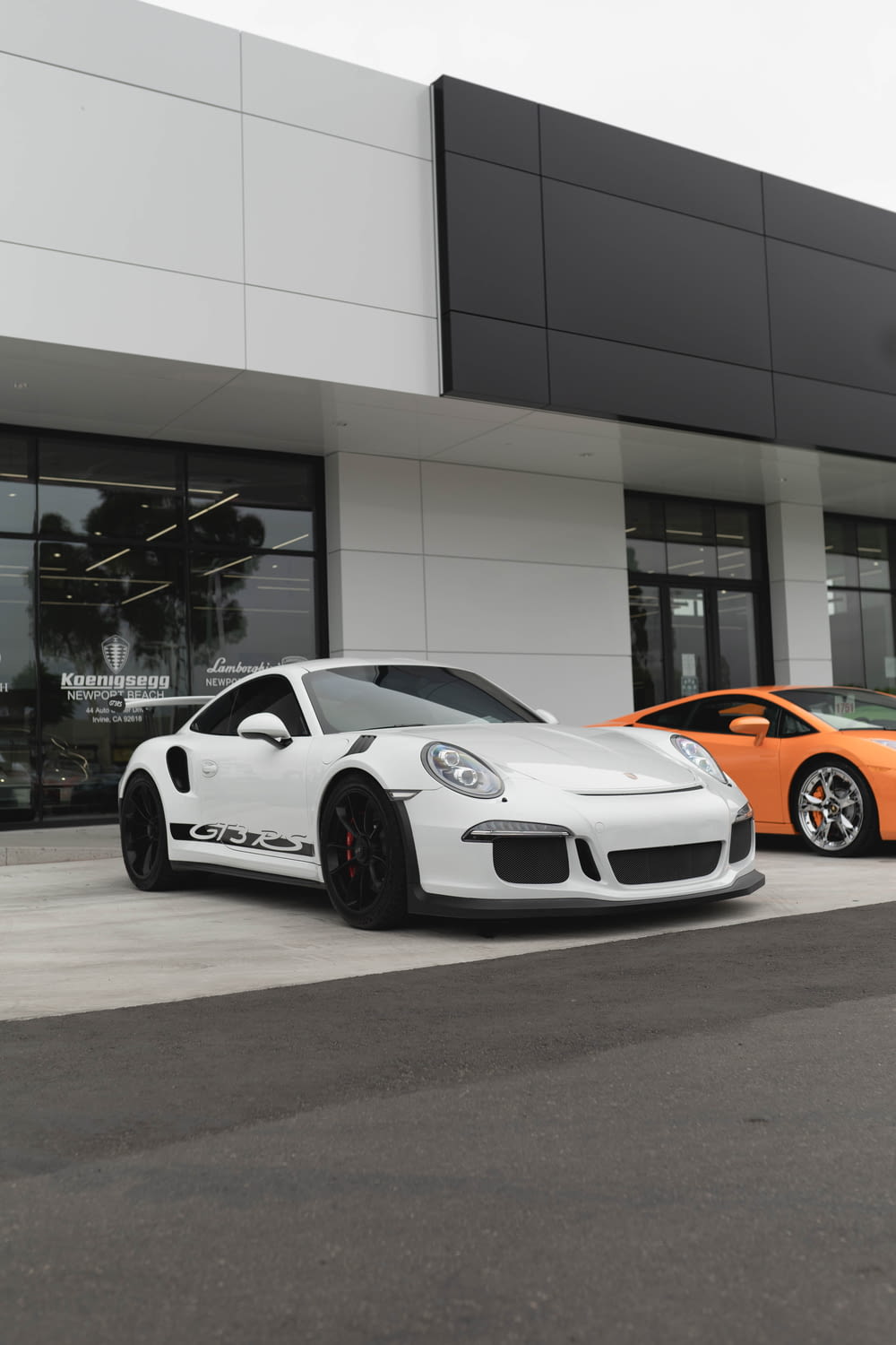 white and orange porsche 911 parked in front of white building