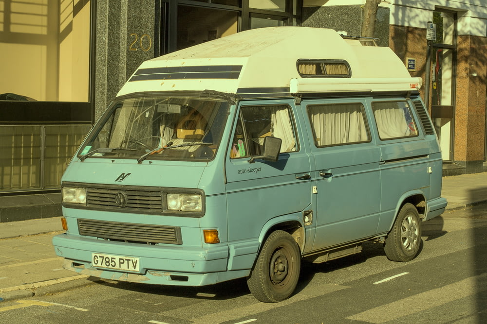 white and teal van parked on sidewalk during daytime