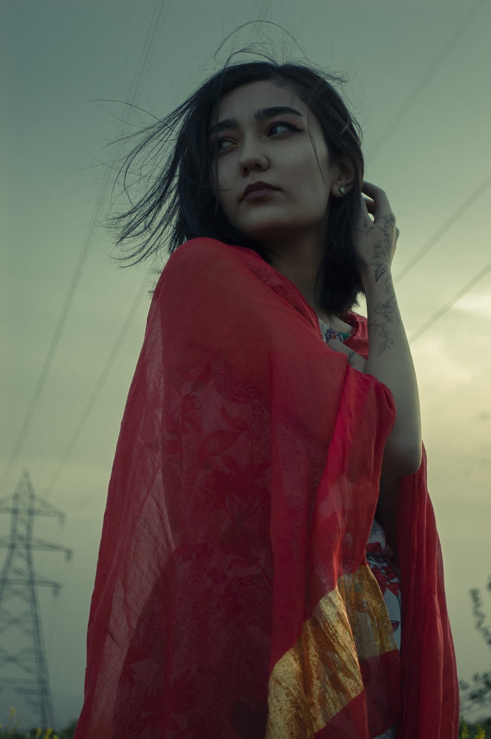 a woman in a red shawl is standing in a field