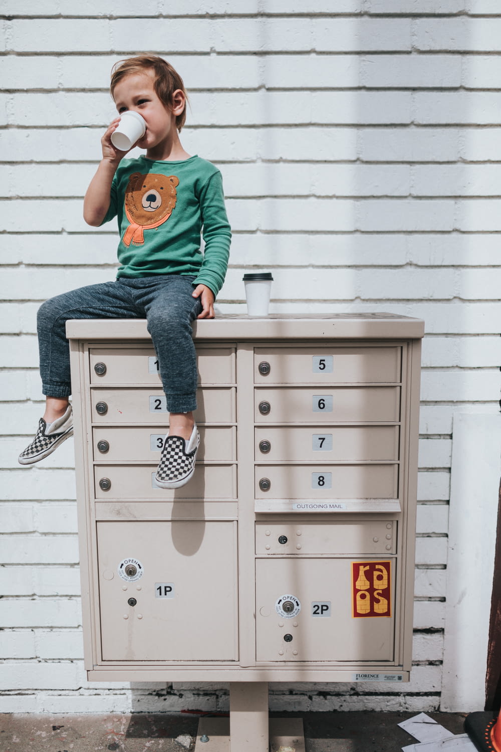 boy in green t-shirt and blue denim jeans sitting on white metal cabinet