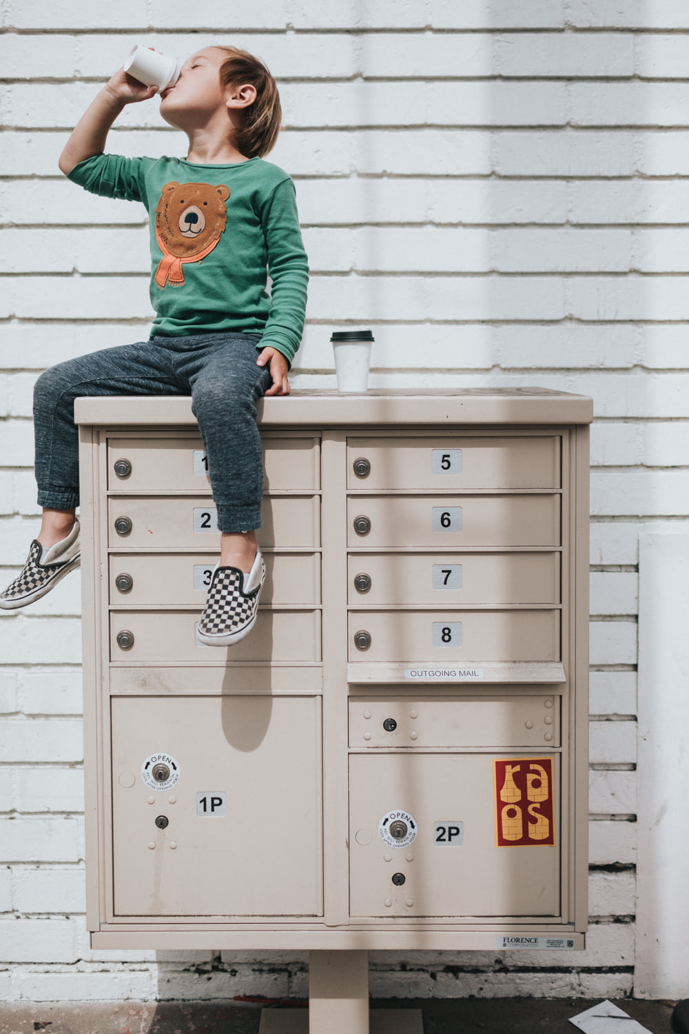 boy in green hoodie and blue denim jeans sitting on gray steel cabinet