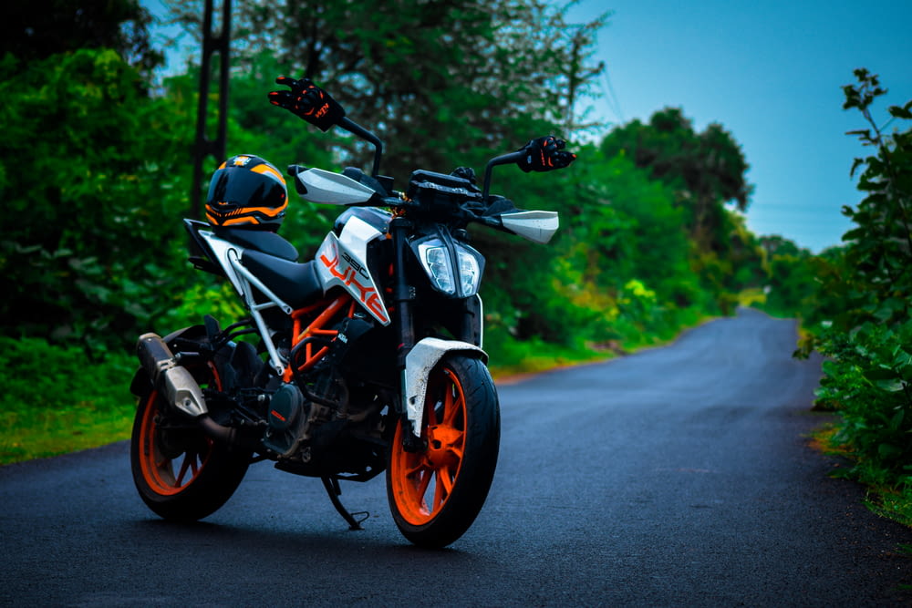 motocicleta preta e laranja na estrada durante o dia