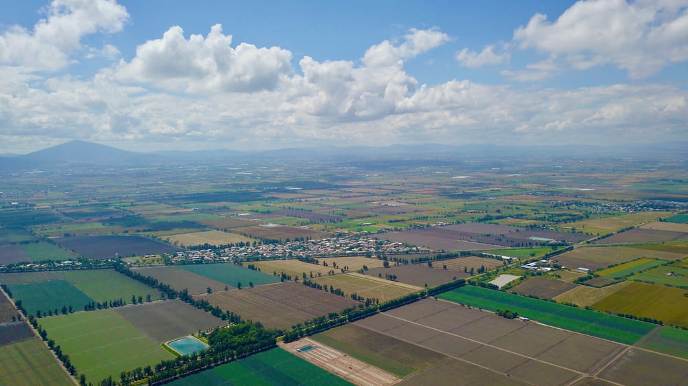 aerial view of green field under cloudy sky during daytime