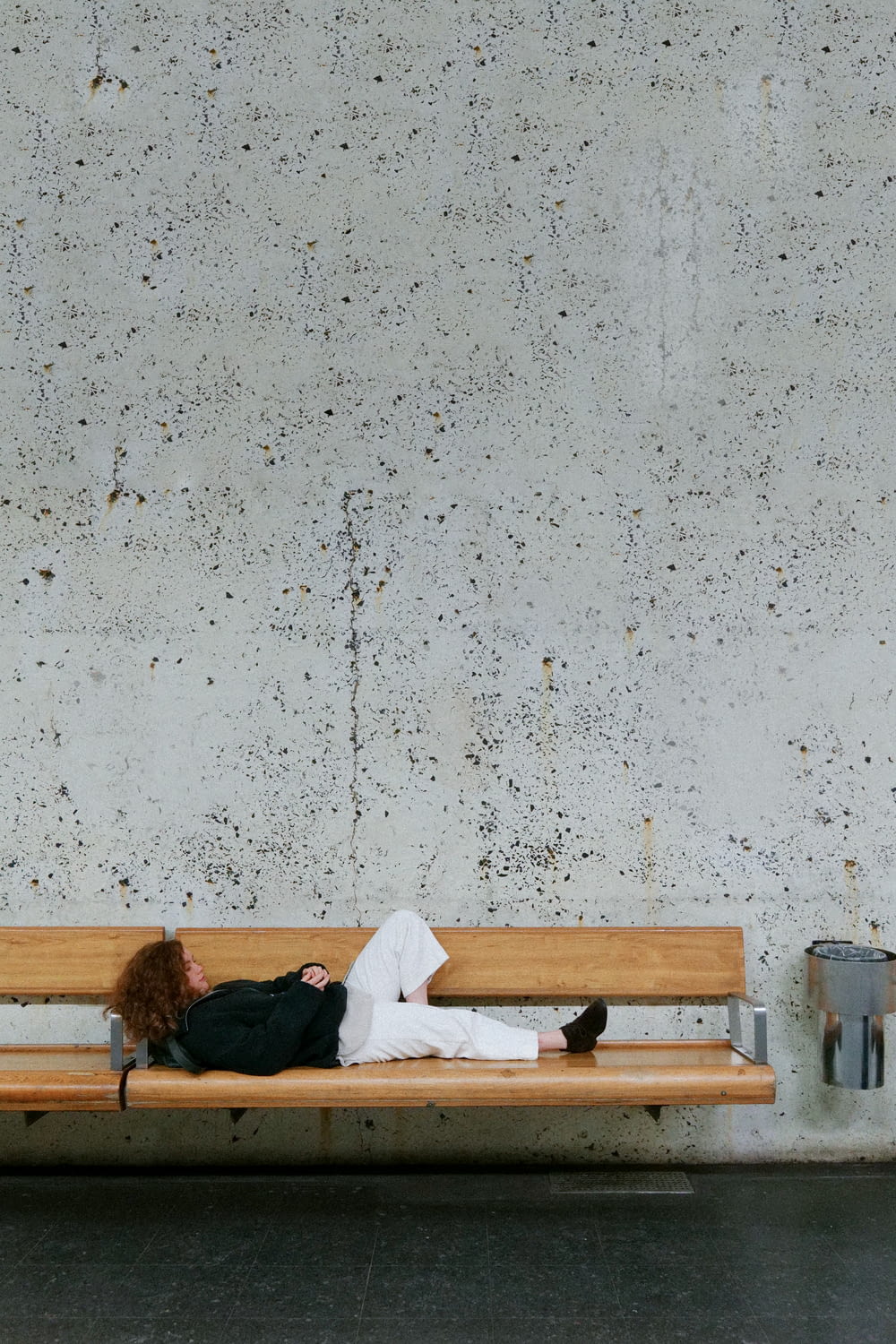 person in white long sleeve shirt lying on brown wooden bench